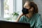 Depressed woman wearing face mask in office at work and looking out of the window. mental health and burnout concept