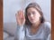 Depressed young lady touching window glass with rain drops, feeling unhappy or melancholic