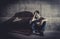 Depressed young man sitting on street ground with shadow on concrete wall