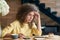 Depressed young woman with curly hair sitting on wooden restaurant`s table.