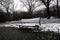 Depressing Ice cold winter mood in city park with a snow covered empty bench.