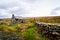 Derelict abandoned building, cottage, with crumbling walls and roof on grass with a blue sky.