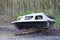 Derelict abandoned fibreglass boat on trailer dumped in waste ground