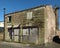 Derelict empty abandoned business premises converted from a house with collapsing walls and boarded up door and window