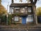 derelict house on a residential street with boarded up windows and decaying crumbling walls