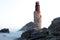 Derelict rusty simple lighthouse on cliffs on seaside in Gisborne in New Zealand washed over by waves