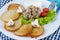 Deruny - potato pancakes with mushrooms, champignons, sour cream on a white plate. Cherry tomatoes, salad. Restaurant