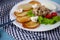 Deruny - potato pancakes with mushrooms, champignons, sour cream on a white plate. Cherry tomatoes, salad. Restaurant serving on a