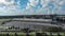 descending aerial footage of Hard Rock Stadium with lush green trees and grass, a river, a parking lot and blue sky