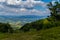 Descent from a high hill into a green valley between thickets of trees