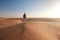 Desert adventure. Young man with backpack walking on sand dune. Dubai, United Arab Emirates