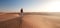 Desert adventure. Young man with backpack walking on sand dune. Dubai, United Arab Emirates