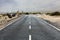 Desert asphalt road with a typical small village of Lanzarote Island on the background, Canary Islands