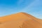 Desert contrast of orange colored sand and bright blue sky in the rolling hills in Ras al Khaimah, in the United Arab Emirates