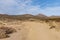 Desert dirt road leading into dry hills beyond