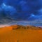 Desert dune under dense dramatic cloudy sky