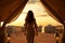 Desert Escape: Silhouette of Woman Embracing Golden Sands from Luxury Tent