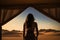 Desert Escape: Silhouette of Woman Embracing Golden Sands from Luxury Tent