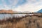 Desert grasses in foreground with lake and cliffs in background at sunset in autumn