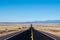 Desert highway in a vast barren landscape with distant mountains