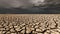 Desert landscape with cracked earth under storm clouds.