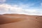 Desert landscape dunes in the afternoon with blue skies white clouds.