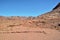 Desert landscape, mountains of red sandstone, a plain covered with rare desert vegetation, a stretch of road with