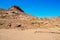 Desert landscape, mountains of red sandstone, a plain covered with rare desert vegetation, a stretch of road with telegraph poles