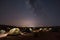 desert night sky with stars and moon shining down on rows of tents