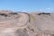 Desert road curve in Atacama: yellow sign and barren landscape of desert