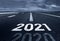 A desert road with the inscription 2021 2020. Concept of the departing old year and new goals