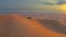 Desert Safari off-road with sunset view. SUV or 4x4 car vehicle rides on desert dune barkhan or sand-dune. Aerial drone