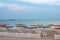 Desert seascape with white deck chairs under colorful beach umbrellas