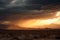 desert storm with view of stormy sunset, with silhouette of mountains in the background