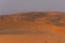 Desert at sunrise brings out bold burnt orange colored sand making a great desert landscape on rippling or rolling hills in Ras al