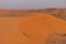 Desert at sunrise brings out bold burnt orange colored sand making a great desert landscape on rippling or rolling hills in Ras al