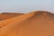 Desert at sunrise brings out bold burnt orange colored sand making a great desert landscape on rippling or rolling hills in Ras al