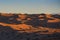 Desert at sunrise brings out bold burnt orange colored sand wiht shadows making a great desert landscape on rippling or rolling