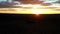 Desert sunset aerial shot over group of people on the dunes wavy sand in silhouette follow by light streak sunlight at