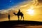 Desert sunset at Jaisalmer Rajasthan with moody sky and tourist on camel in silhouette