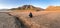 Desert. A teenager squatting on the cracked earth. Dried-up riverbed. Background of mountain
