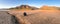 Desert. A teenager squatting on the cracked earth. Dried-up riverbed. Background of mountain