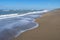 Deserted beach in Florida with foam-edged waves breaking on the sand under a blue sky