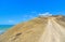 Deserted dirt road on a promontory towards the sea and lonely beach in summer day