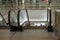 A deserted escalator fenced with a glass fence in a shopping center leads to the lower floor