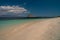 Deserted island coast scene in bright afternoon rock formation island in the ocean footsteps on the beach sand. Sumbawa