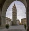 Almost deserted Piazza del Duomo framed by an arch of the Palazzo del Comune, Pistoia, Tuscany, Italy