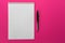 Design concept - Top view of a spiral school notebook and pens collection on a pink background for layout.