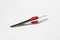 Designer metal tweezers with red plastic insert on a white background