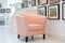 designer peach armchair in a gallerystyle white room with framed pictures